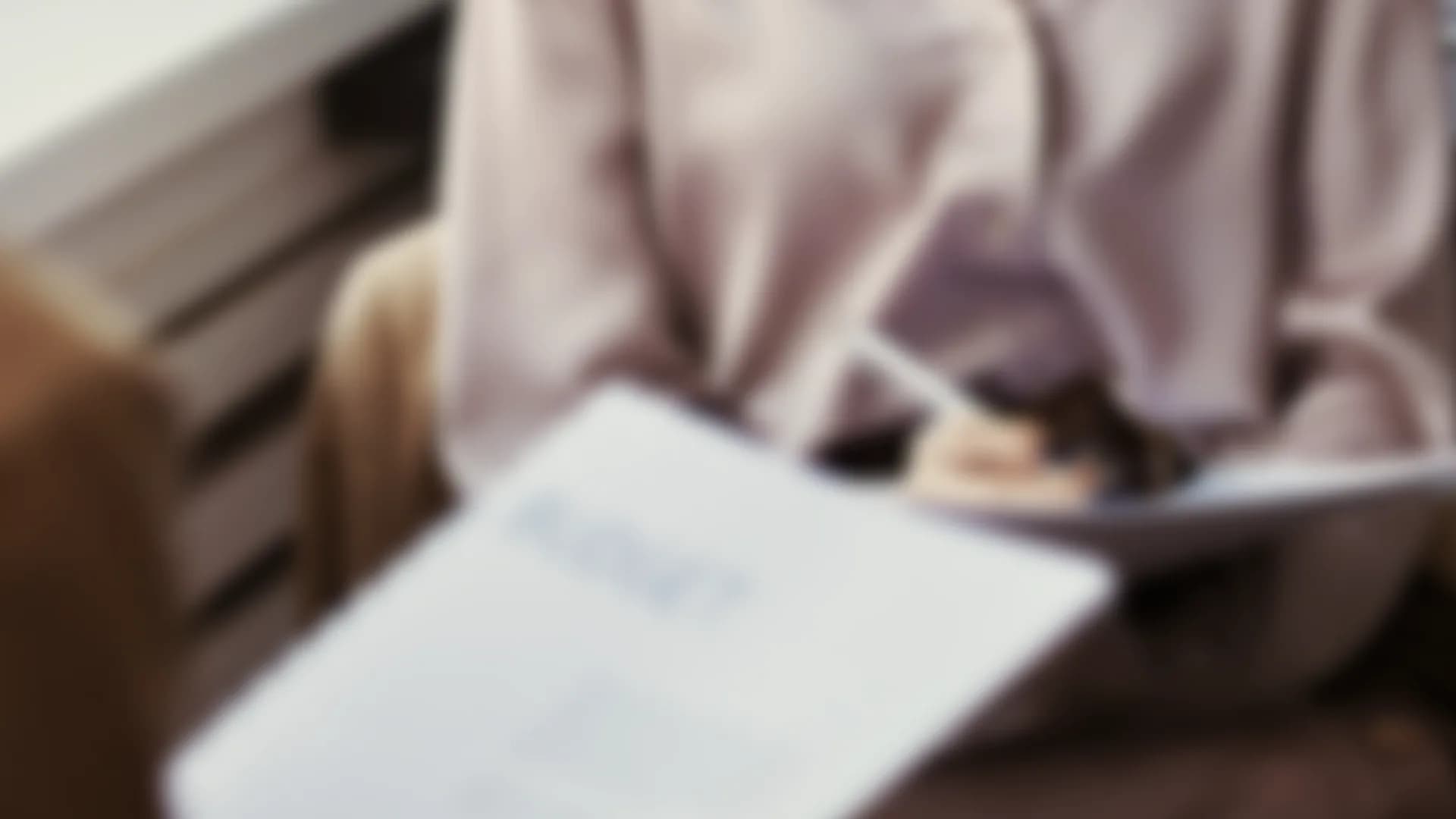A person holding a printed report on a sofa, out of focus