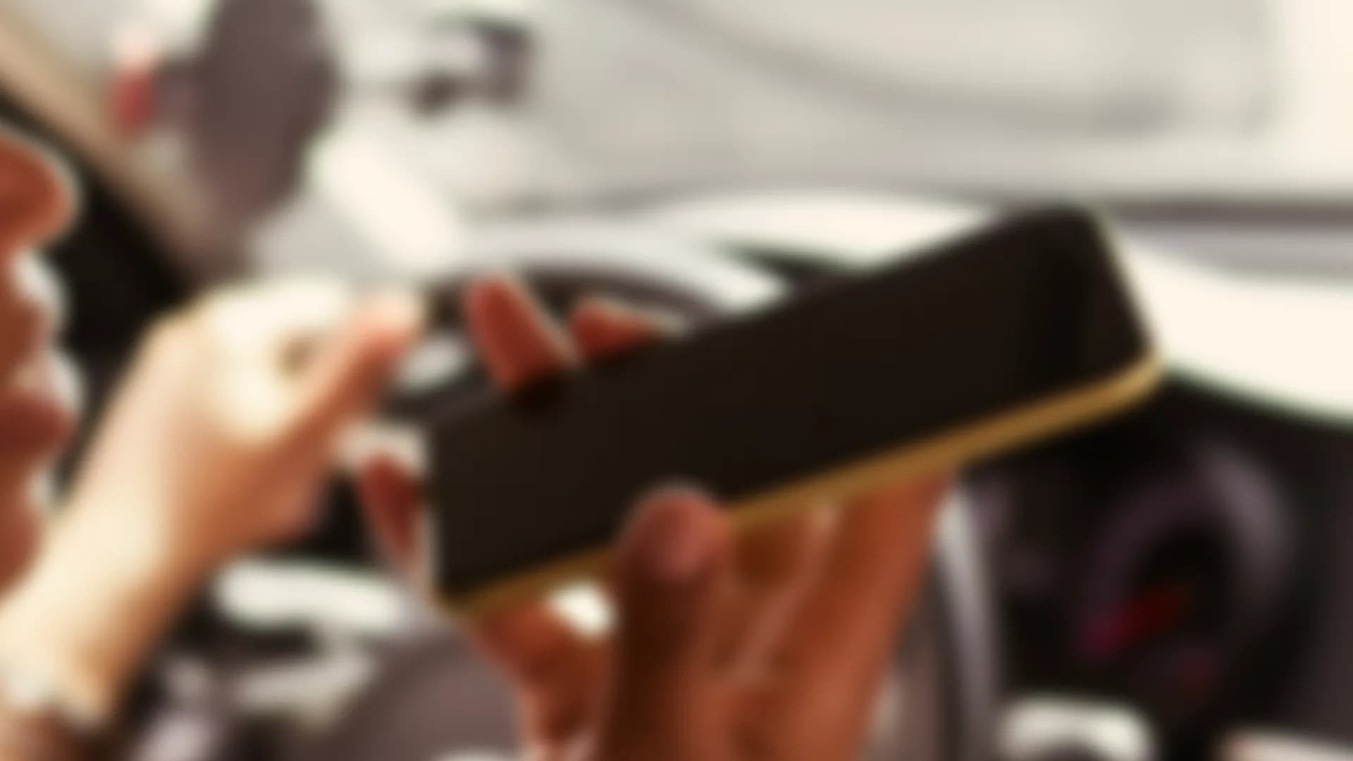 A driver holding a phone in a car, out of focus